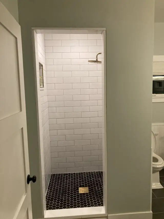 White subway tile shower walls with a ceiling rain shower head