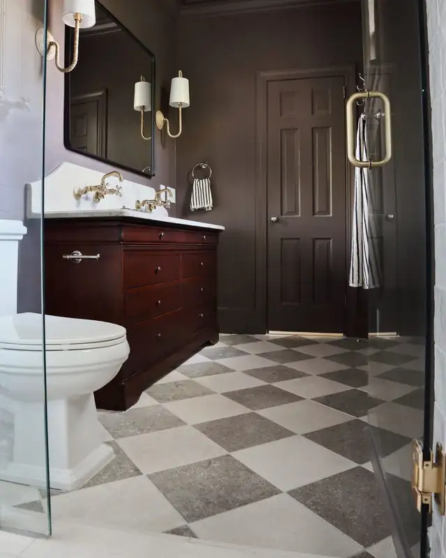 Bathroom with gray and white checkerboard floor tile, dark cherry vanity and glass shower